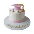 Personalised pink graduation cake with white quilted fondant, gold pearl details, pink mortarboard, gold tassel, rolled diploma, flowers and congratulatory message