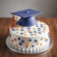 Ivory Graduation Day Cake with navy mortarboard, orange-gold tassel, rolled diploma, blue and gold stars and white piped border