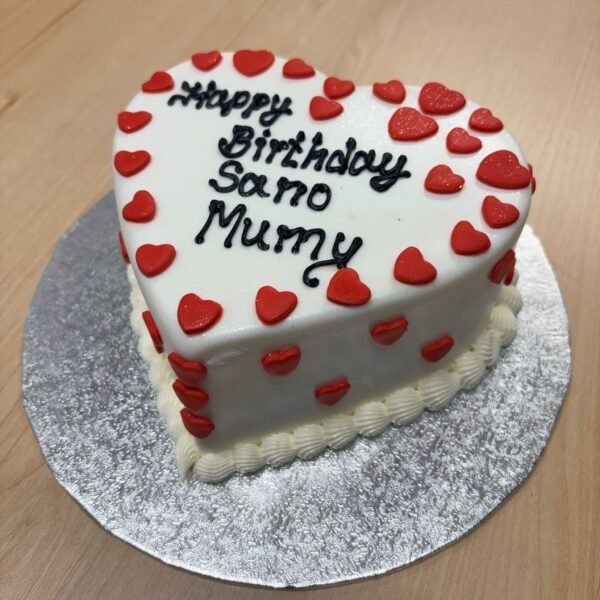 Personalised white heart-shaped cake with scattered raised red hearts, black message lettering and a white shell-piped base