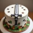 White Minecraft iron sword cake with a large grey-and-black pixel sword, brown fondant tiles and a green grass-and-dirt block border