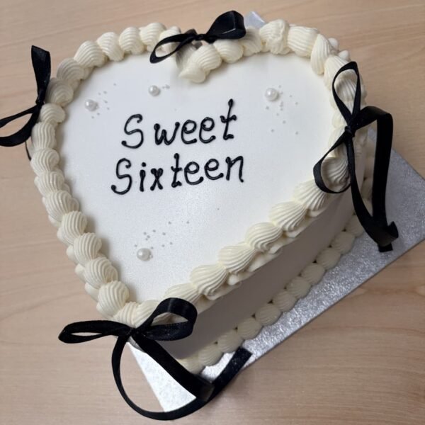 White vintage heart cake with ivory shell piping, pearl-style accents, black ribbon bows and a custom centre message