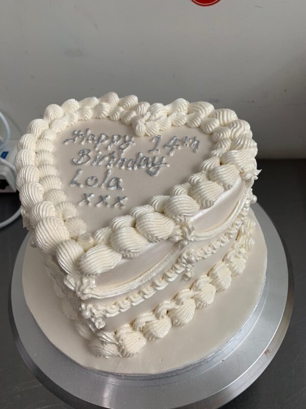 All-white vintage Lambeth heart cake with layered shell piping, scalloped swags, pearl accents and a silver custom message