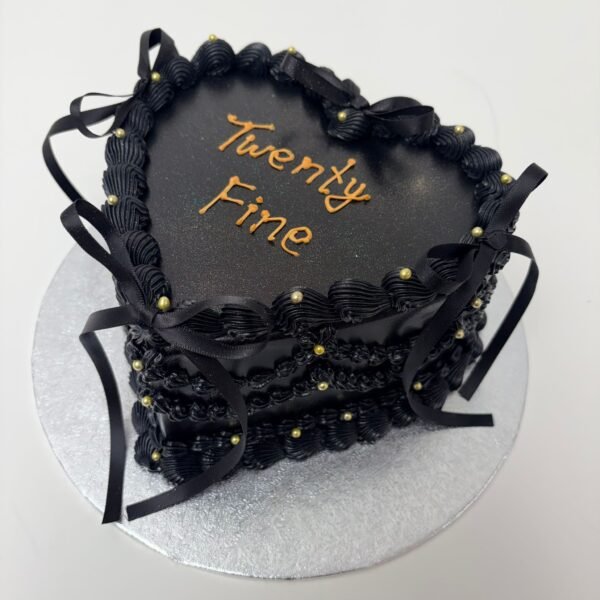 All-black vintage Lambeth heart cake with ornate layered piping, scalloped swags, black ribbon bows, gold pearl accents and custom message