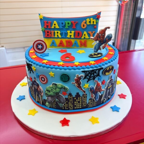 Blue comic-city superhero cake with Hulk, Captain America, Spider-Man and Batman artwork, personalised Aadam age-six banner, skyline and stars