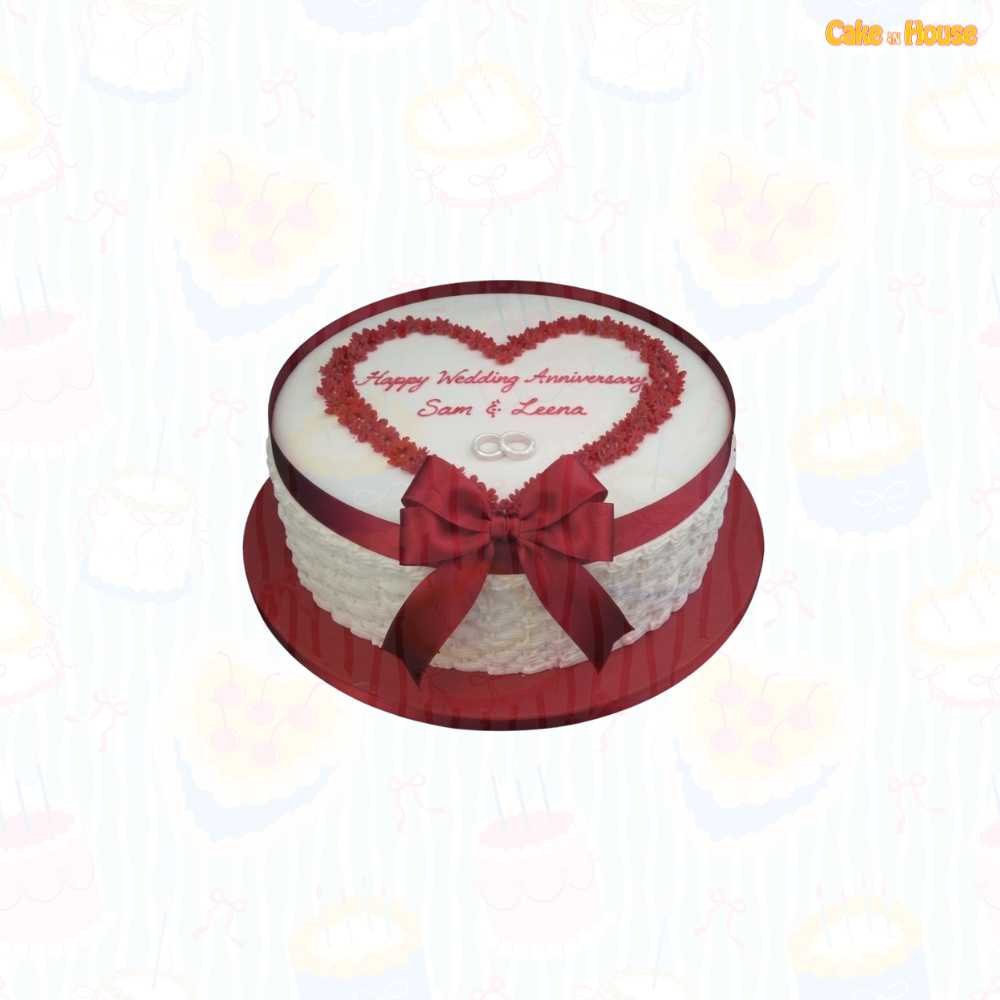 White round wedding anniversary cake with burgundy piped heart frame, custom couple message, silver wedding rings, textured sides and large ribbon bow