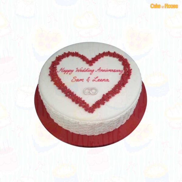 Round white wedding anniversary cake with a red piped heart frame, personalised couple message, silver wedding rings and textured icing sides