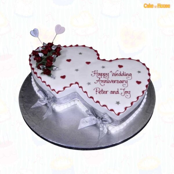 Interlocking double-heart anniversary cake with white icing, burgundy borders, red roses, silver leaves, ribbon bows, heart toppers and custom couple message