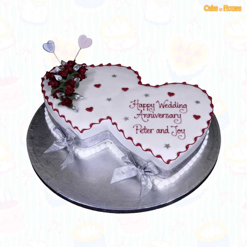 Interlocking double-heart anniversary cake with white icing, burgundy borders, red roses, silver leaves, ribbon bows, heart toppers and custom couple message