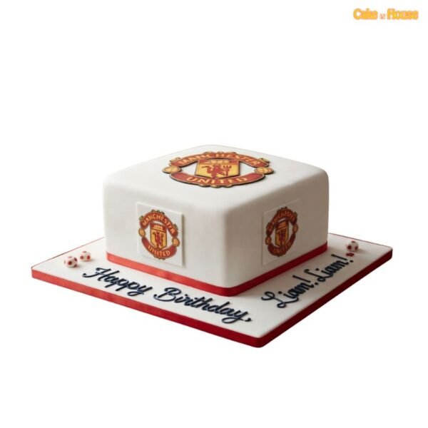 Square white Manchester United football cake with club crests on the top and sides, red ribbon trim and miniature football decorations