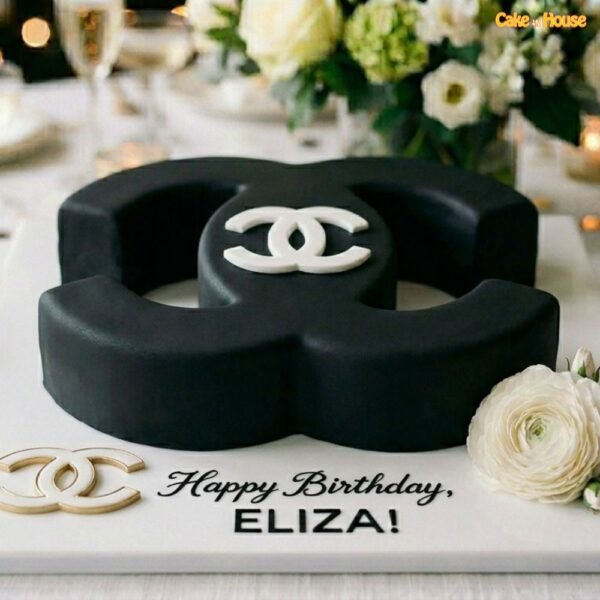 Black Chanel logo birthday cake with sculpted CC-style shape, white logo detail, gold accents and personalised birthday message