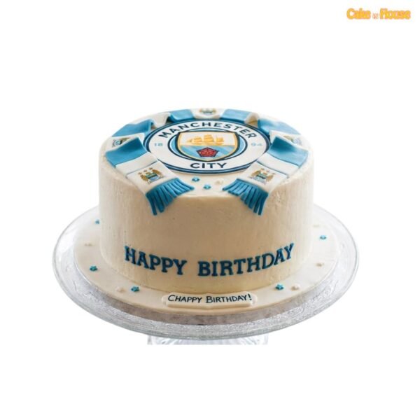 Round ivory Manchester City birthday cake with large club crest, blue-and-white football scarf, blue star details and personalised message