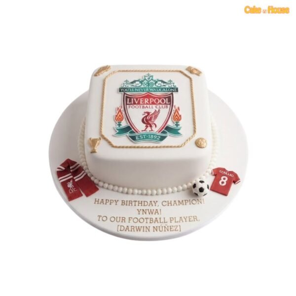 White square Liverpool FC birthday cake with large club crest, gold rope edging, miniature scarf, football shirt, trophy and football decorations